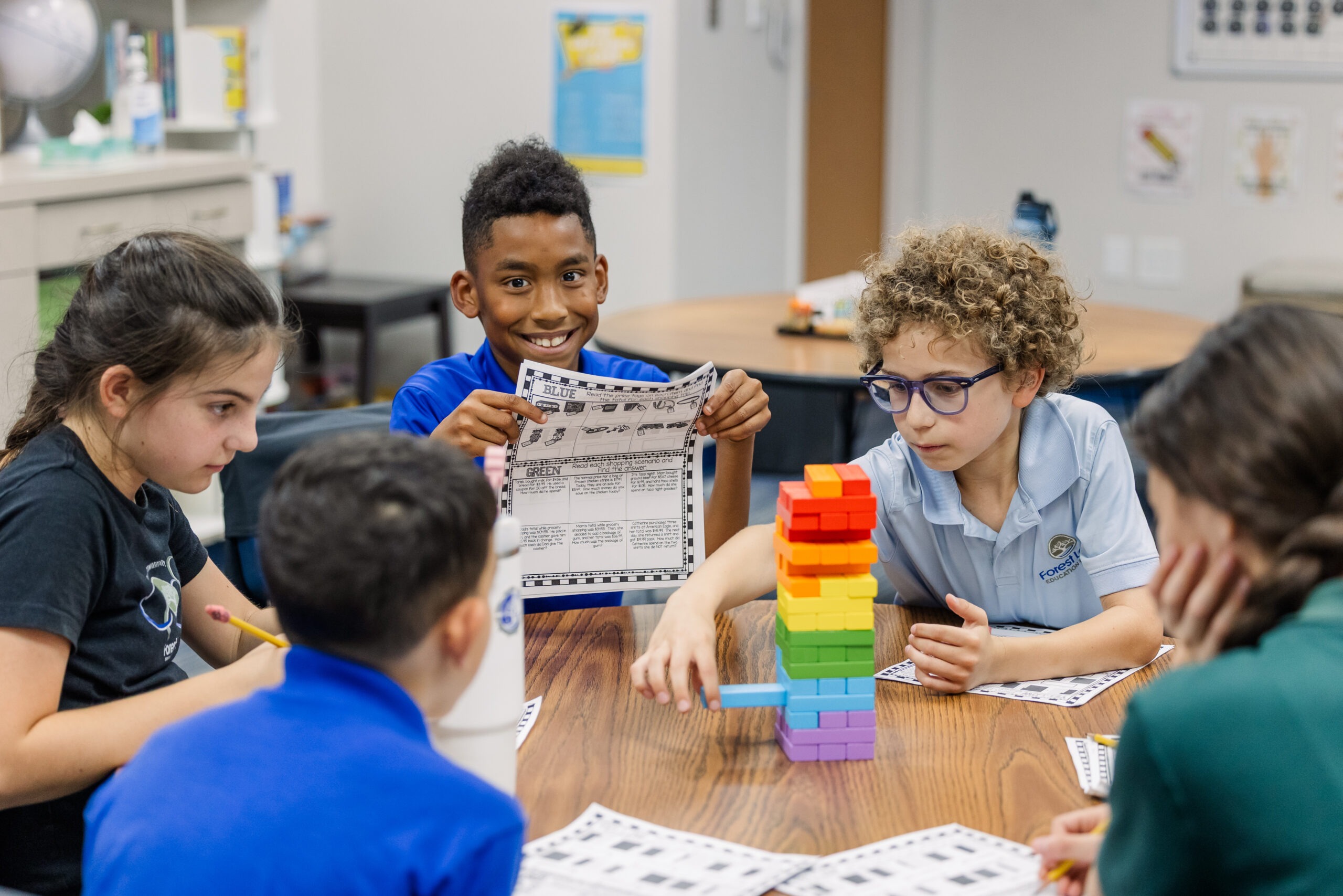 Forest Lake Education Center students collaborating around a colorful wooden block tower at a classroom table during a hands-on learning activity