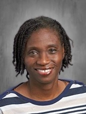Portrait of a smiling Black woman with short twists, wearing a navy and white striped top against a gray studio backdrop.