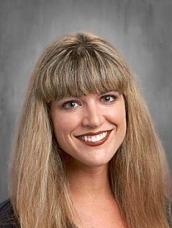 Portrait of a smiling woman with long blonde hair and bangs facing the camera.