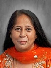 Portrait of a woman with dark hair wearing an orange embroidered scarf and dress, looking at the camera.