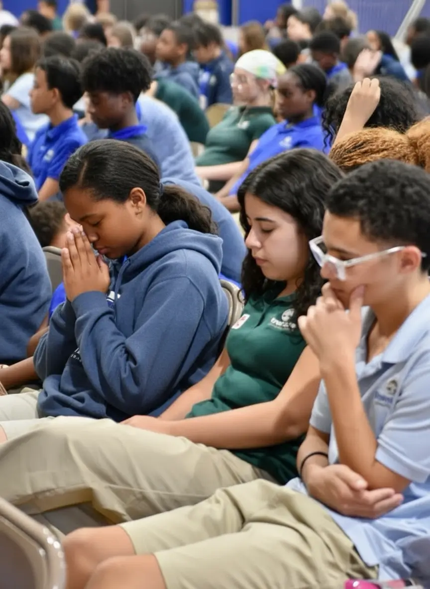 Forest Lake Education Center students in school uniforms with eyes closed in reverent prayer during chapel